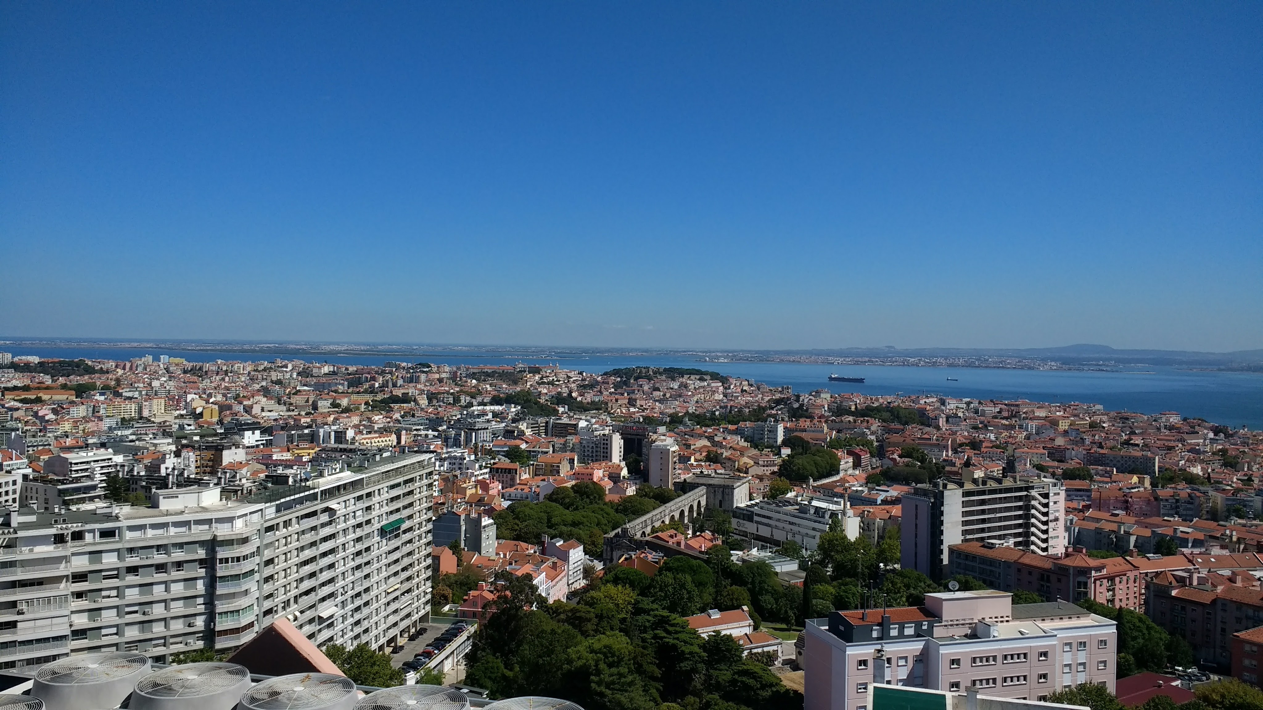 Photo of Lisbon taken from a hill overlooking the city in daytime. 